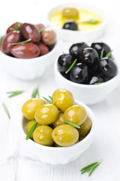 Three kinds of olives in bowls, fresh rosemary and olive oil — Free Stock Photo