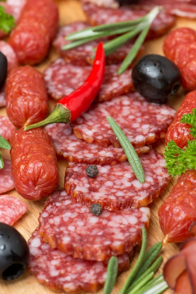 Assorted meats and sausages on a wooden board, close-up — Stock Photo, Image