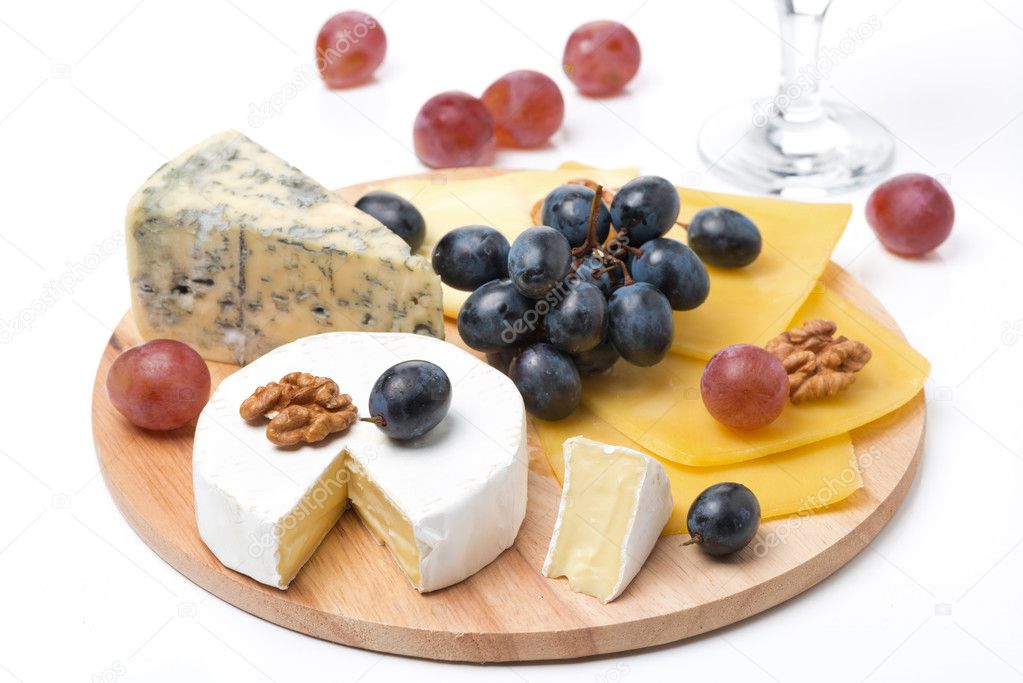 Assorted cheeses, grapes and glass of wine on wooden board