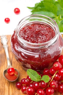 Berry reçeli cam kavanoz ve ahşap tahta üzerinde taze kırmızı kuş üzümü