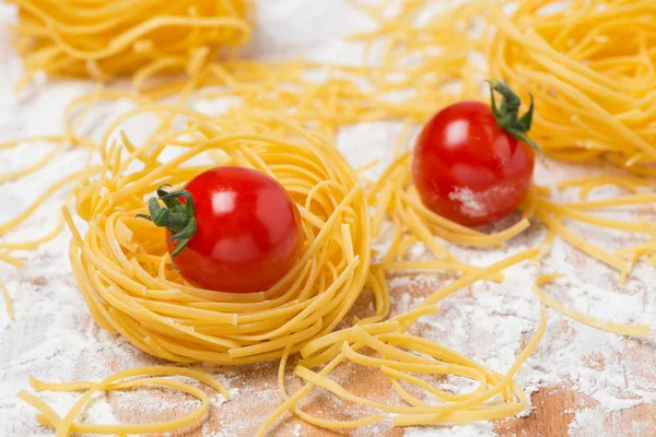 Gniazdo jajko włoski makaron, pomidory na pokładzie cięcia — Zdjęcie stockowe
