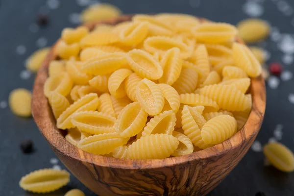 Italian pasta shells in a wodden bowl, close-up, selective focus — Stock Photo, Image