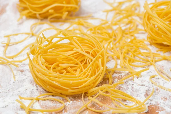 Italian egg pasta nests on a floured cutting board — Stock Photo, Image