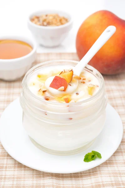 Домашний йогурт с медом, персиками, орехами в ложке — стоковое фото