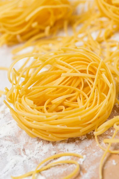Italian egg pasta nests on a floured cutting board, close-up — Stock Photo, Image