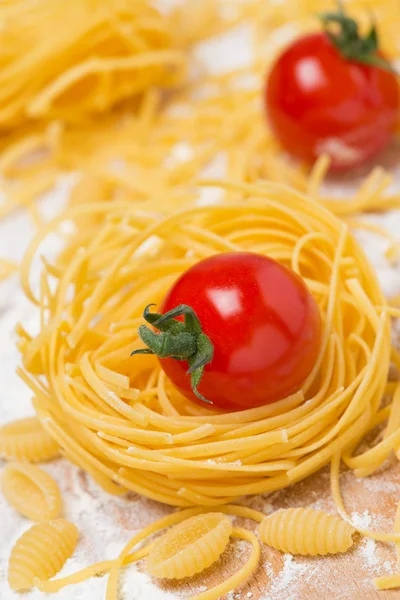 Italian egg pasta nest, cherry tomatoes on a cutting board — Stock Photo, Image