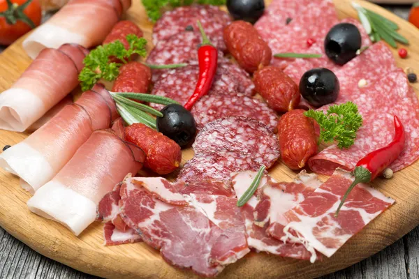 Assorted meats and sausages, olives and spices, close-up — Stock Photo, Image