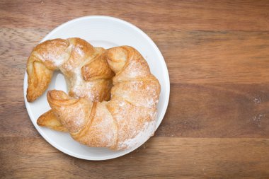 ahşap arka plan üzerinde bir tabakta kruvasan