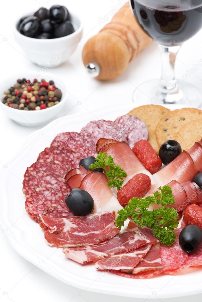 Assorted meat delicacies on a plate and a glass of wine