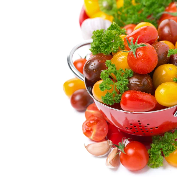 Assorted cherry tomatoes in a colander and fresh herbs, isolated — Stock Photo, Image