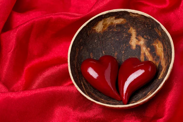 Two hearts in a bowl of coconut on red satin background — Stock Photo, Image