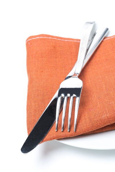 Serving - fork, knife and napkin on a plate, isolated, close-up