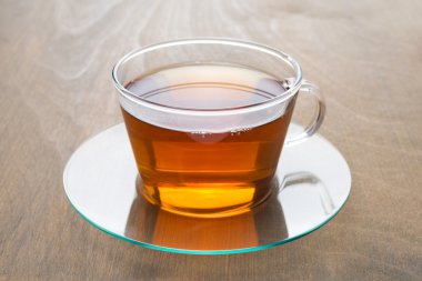 şeffaf cam ahşap arka plan üzerinde siyah çay fincan