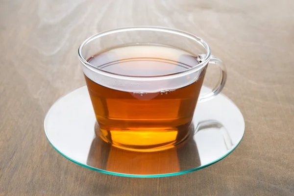 लाकडी पार्श्वभूमीवर काळ्या चहाचा पारदर्शक काच कप — स्टॉक फोटो, इमेज