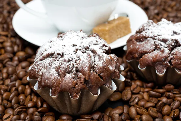 Schokoladenmuffin und Cappuccino auf Kaffeebohnen — Stockfoto