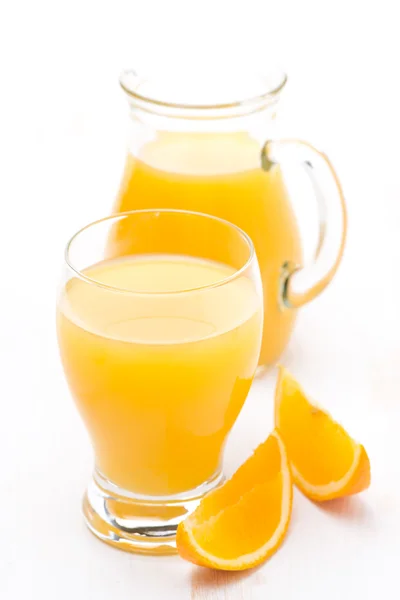 Glass and jug of orange juice and fresh orange slices — Stock Photo, Image