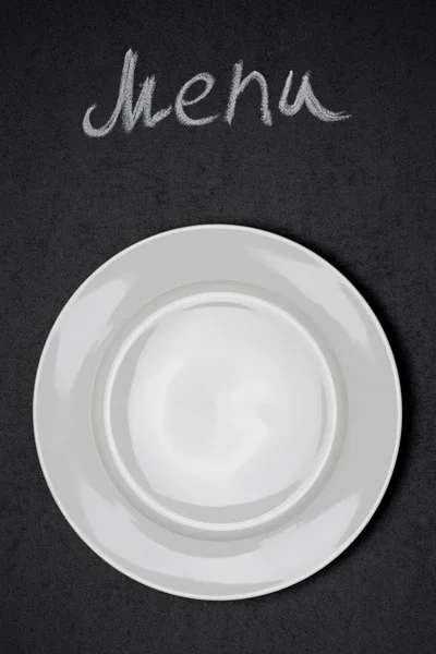 Título del menú escrito con tiza y plato blanco sobre pizarra negra — Foto de Stock