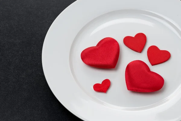 Red hearts on a white plate, a festive serving element, close-up — Stock Photo, Image