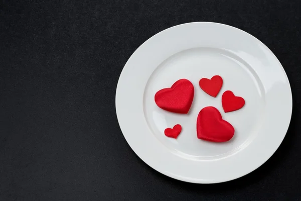 Red hearts on a white plate, a festive serving element — Stock Photo, Image