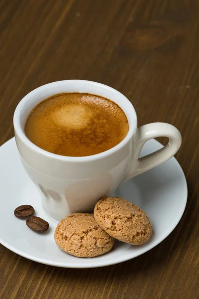 Šálek kávy a biscotti na dřevěný stůl — Stock fotografie