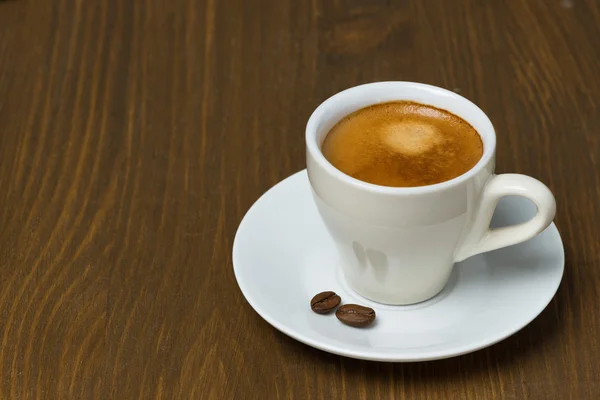 Kopp kaffe med skum på ett träbord — Stockfoto