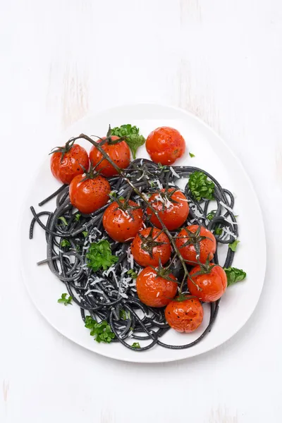 Černé těstoviny s pečenými rajčaty, pohled shora — Stock fotografie