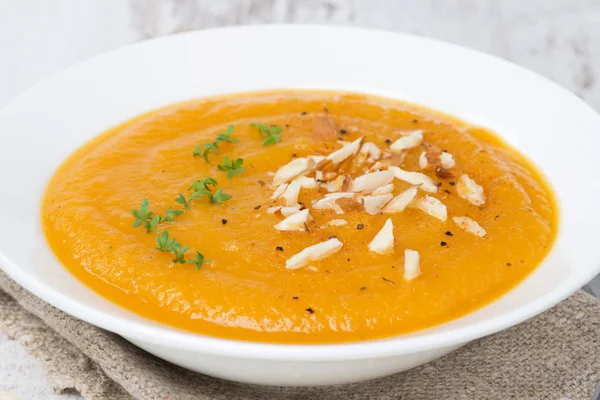 Carrot soup with almonds and watercress on white wooden table — Stock Photo, Image