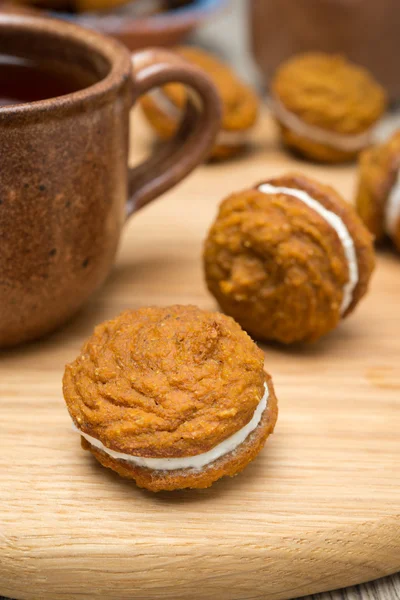 Pumpkin cookies with cream filling and a cup of tea, close-up — Stock Photo, Image