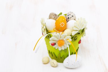 Beyaz ahşap masa üstünde Paskalya yumurtaları sepetle
