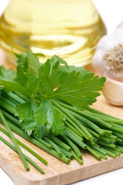 Gräslök, persilja, vitlök och olivolja på en planka, närbild — Stockfoto