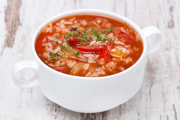 Soupe de tomates avec riz et légumes sur table en bois blanc — Photo