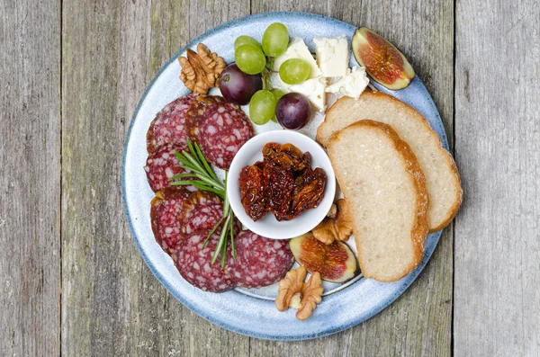 Piatto di spuntini - salsiccia, pane, fichi, uva, noci — Foto Stock