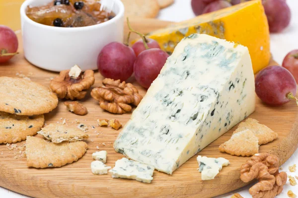 Käse mit Schimmel, Trauben, Cracker, Marmelade und Nüssen auf einem Brett — Stockfoto