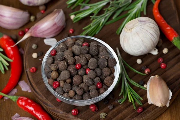 Gedroogde pepers, knoflook, Chili en rozemarijn op een houten bord — Stockfoto