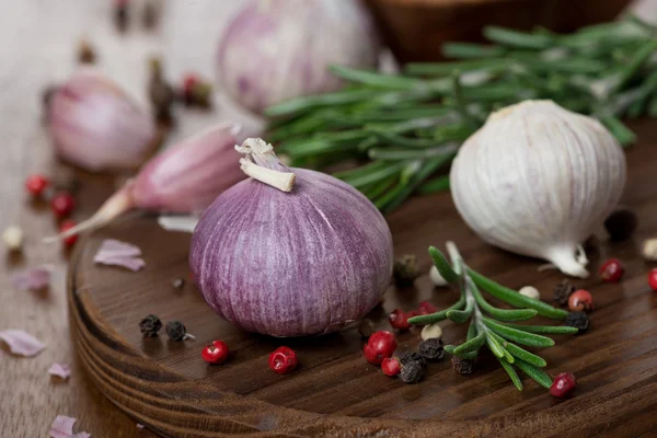 Knoflook, rozemarijn, zeezout en specerijen op houten bord — Stockfoto