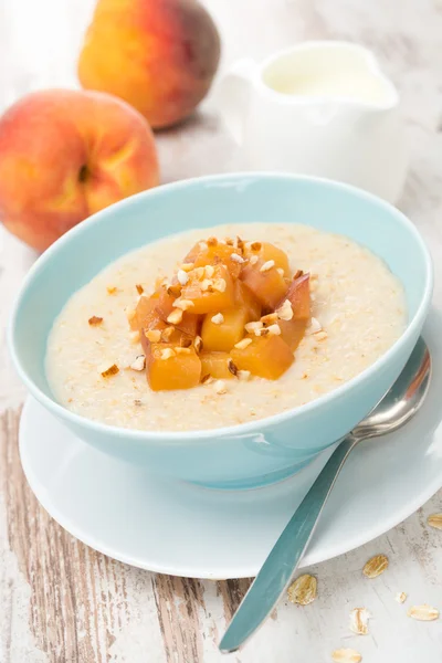Havregrynsgröt med karamelliserade persikor i en skål och kanna yoghurt — Stockfoto