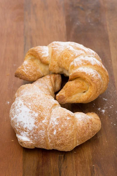 Dos croissants frescos sobre un fondo de madera — Foto de Stock