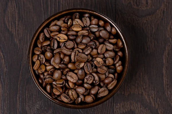 Tazón de granos de café sobre un fondo oscuro, vista superior — Foto de Stock