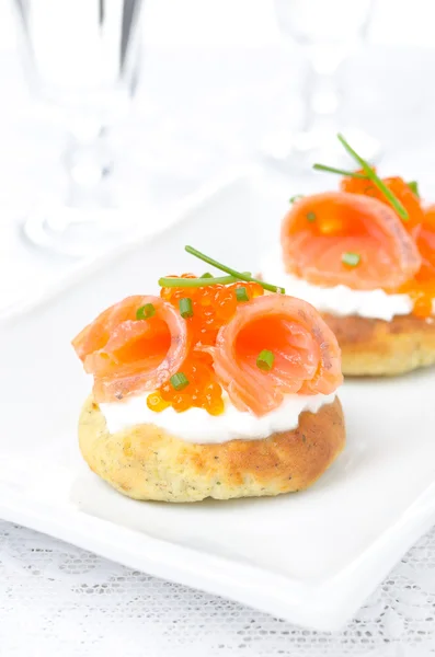 Potato bun with salted salmon, red caviar and chives, vertical — Stock Photo, Image