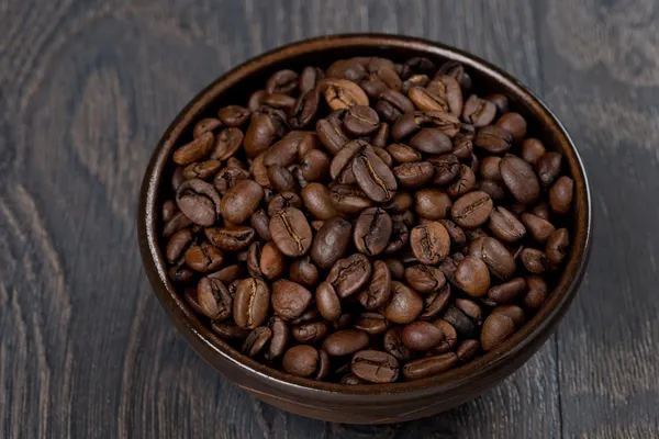 Tigela de grãos de café em um fundo escuro, close-up — Fotografia de Stock