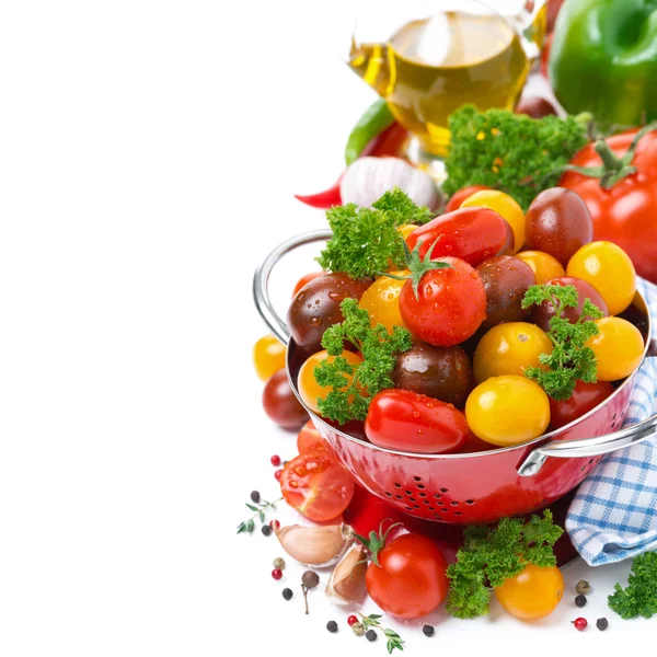 Assorted cherry tomatoes in a red colander, spices, olive oil — Stock Photo, Image