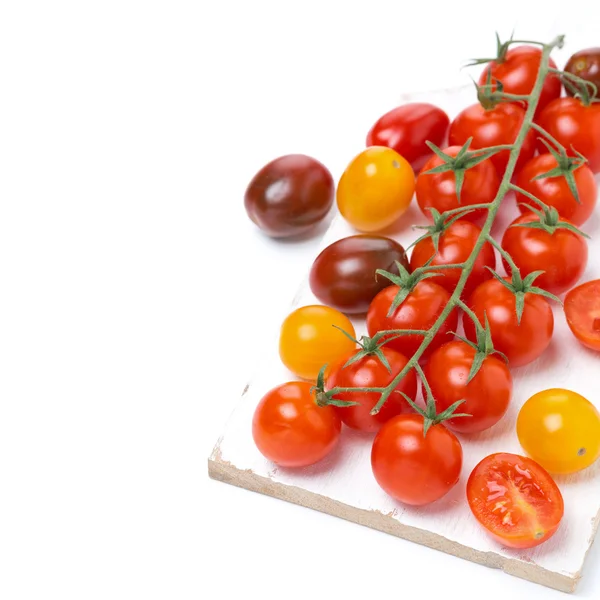 Kleurrijke cherry tomaten op een houten bord, geïsoleerd — Stockfoto