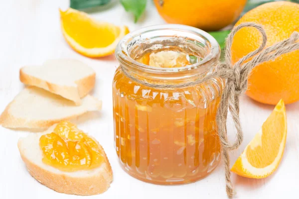 Engarrafamento de laranja em um jarro de vidro e pão fresco — Fotografia de Stock