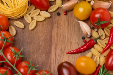farklı makarna, baharat ve ahşap tahta üzerinde domates