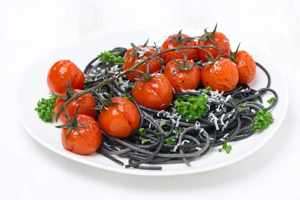 Svart spaghetti med bakade tomater och persilja på plattan — Stockfoto