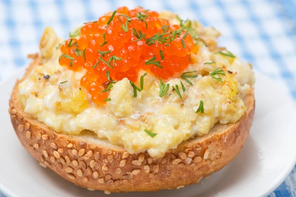 Scramble eggs with red caviar on a wheat bun — Stock Photo, Image