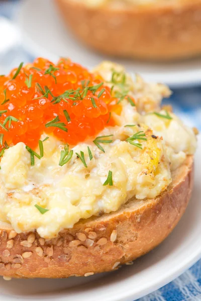 Revueltos huevos con caviar rojo en un bollo de trigo, primer plano — Foto de Stock