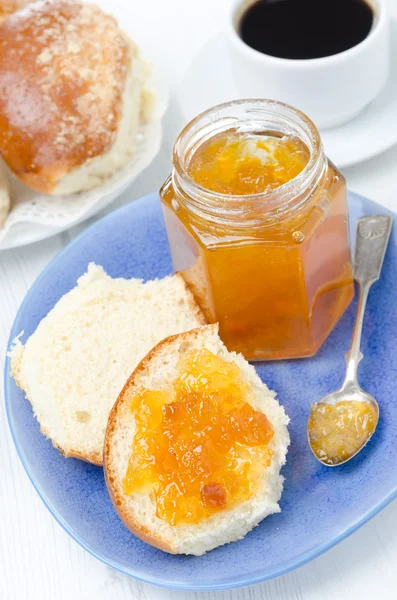 Sweet bun with apricot jam and coffee for breakfast — Stock Photo, Image