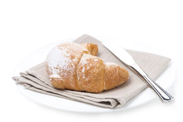 Croissant en een mes op een witte plaat, geïsoleerd — Stockfoto