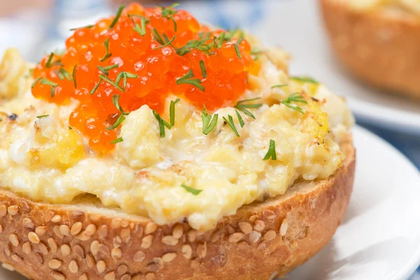 Scramble eggs with red caviar on a bun close-up — Stock Photo, Image
